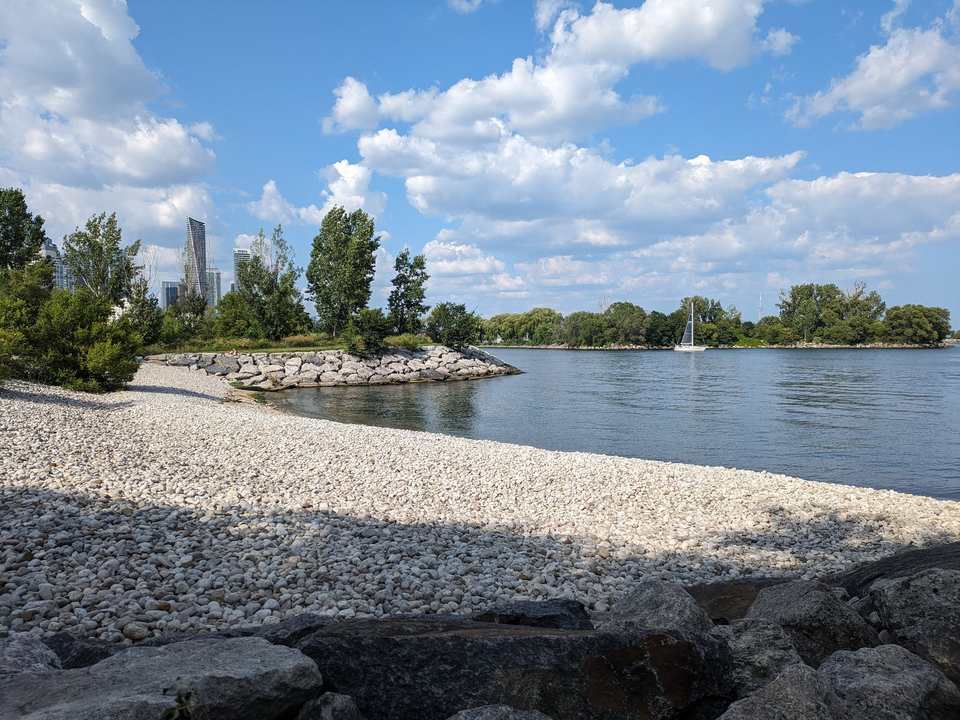 Pebble beach and stone breakwater at Mimico Waterfront Park, Etobicoke, with Lake Ontario beyond